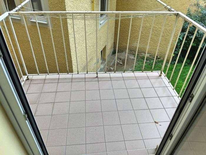 Kleiner Balkon mit Fliesenboden und weißem Metallgeländer.