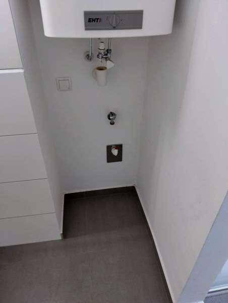 Kleiner Abstellraum mit Anschlüssen für Waschmaschine und Warmwasserbereiter, praktisch und funktional.