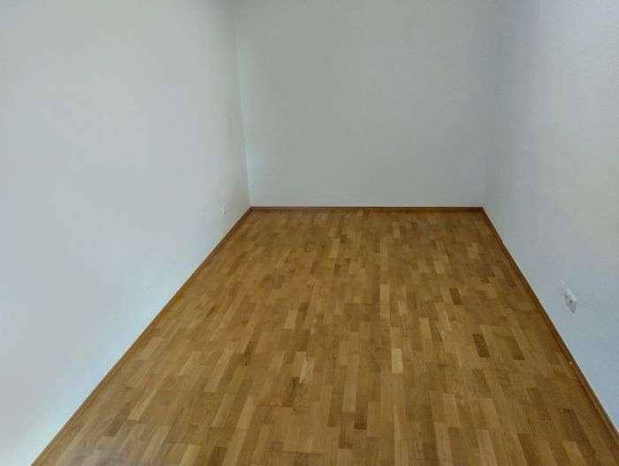 Leerer Raum mit Parkettboden und weißen Wänden, bereit zur individuellen Gestaltung.