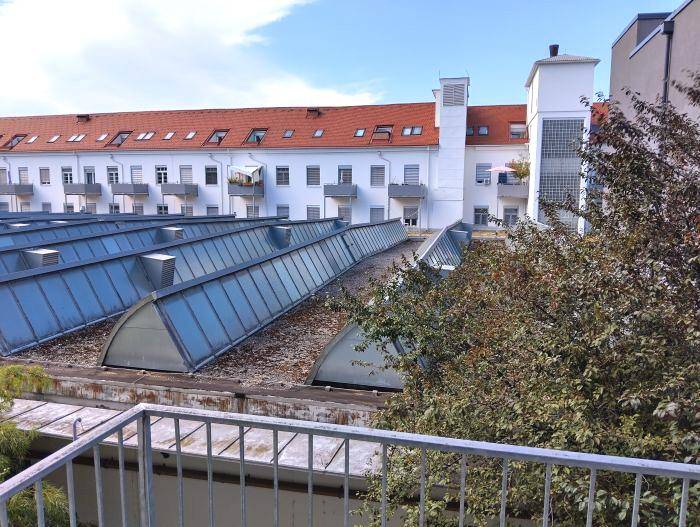 Blick von einer Dachterrasse über Dächer mit roten Ziegeln und modernen Dachfenstern.