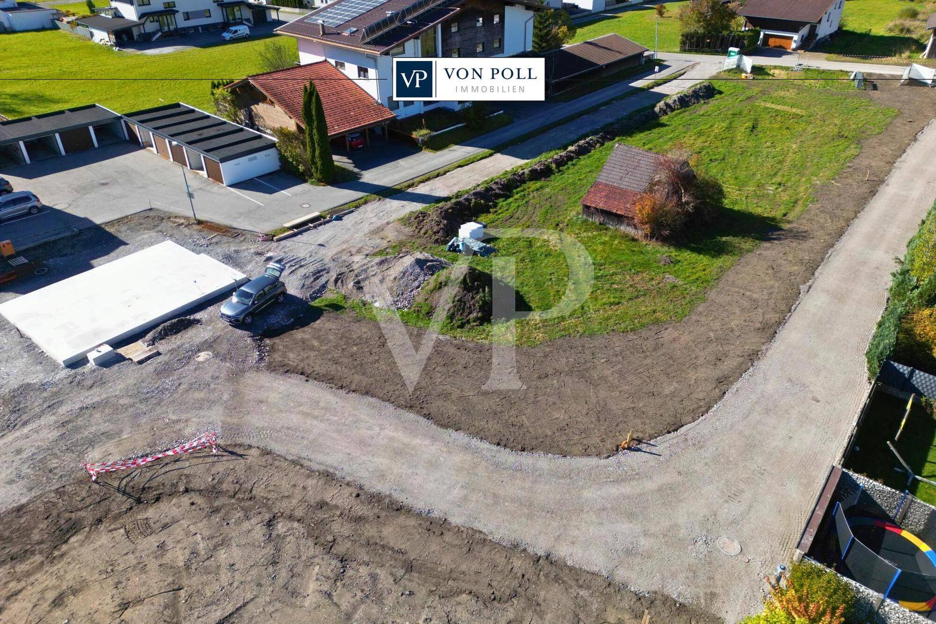 Luftaufnahme eines Baugebiets mit vorbereiteten Grundstücken, umgeben von Garagen und Wohnhäusern.