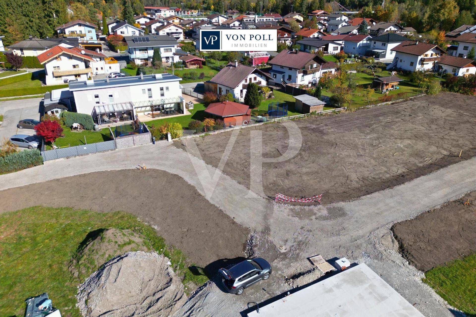 Luftaufnahme eines Baugebiets mit erschlossenen Grundstücken und angrenzenden Einfamilienhäusern.