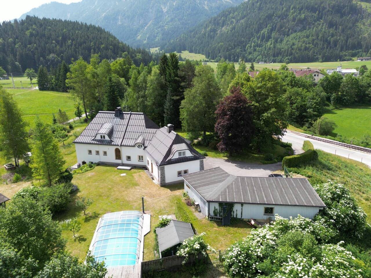 Luftaufnahme des Anwesens mit Haupthaus, Nebengebäude, Pool und weitläufigem Garten in Berglandschaft.