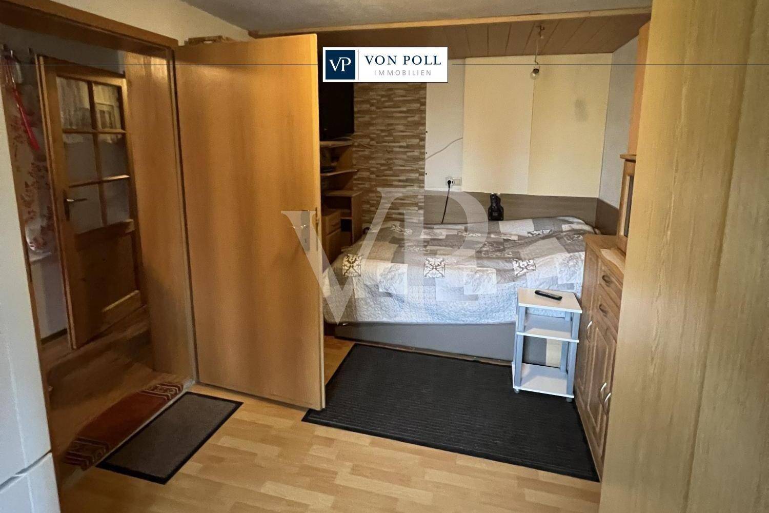 Schlafzimmer mit Doppelbett, Holzmöbeln und Laminatboden, das Gemütlichkeit ausstrahlt.