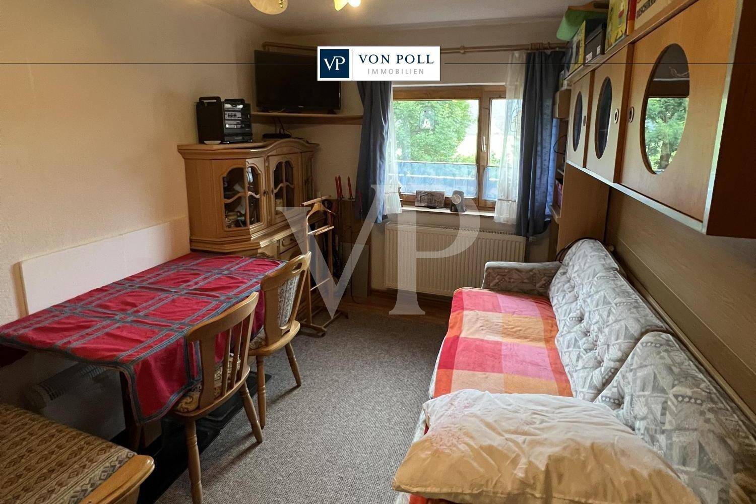 Kleiner Wohnbereich mit Sofa, Esstisch und Blick aus dem Fenster in die Umgebung.