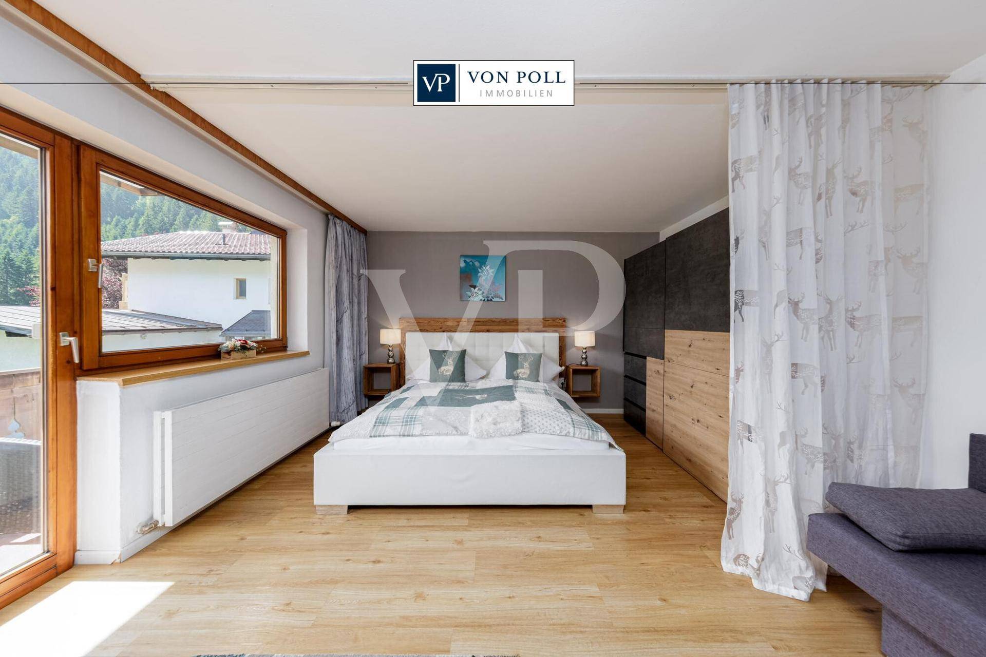 Geräumiges Schlafzimmer mit Doppelbett, Holzboden und großem Fenster mit Blick ins Grüne.