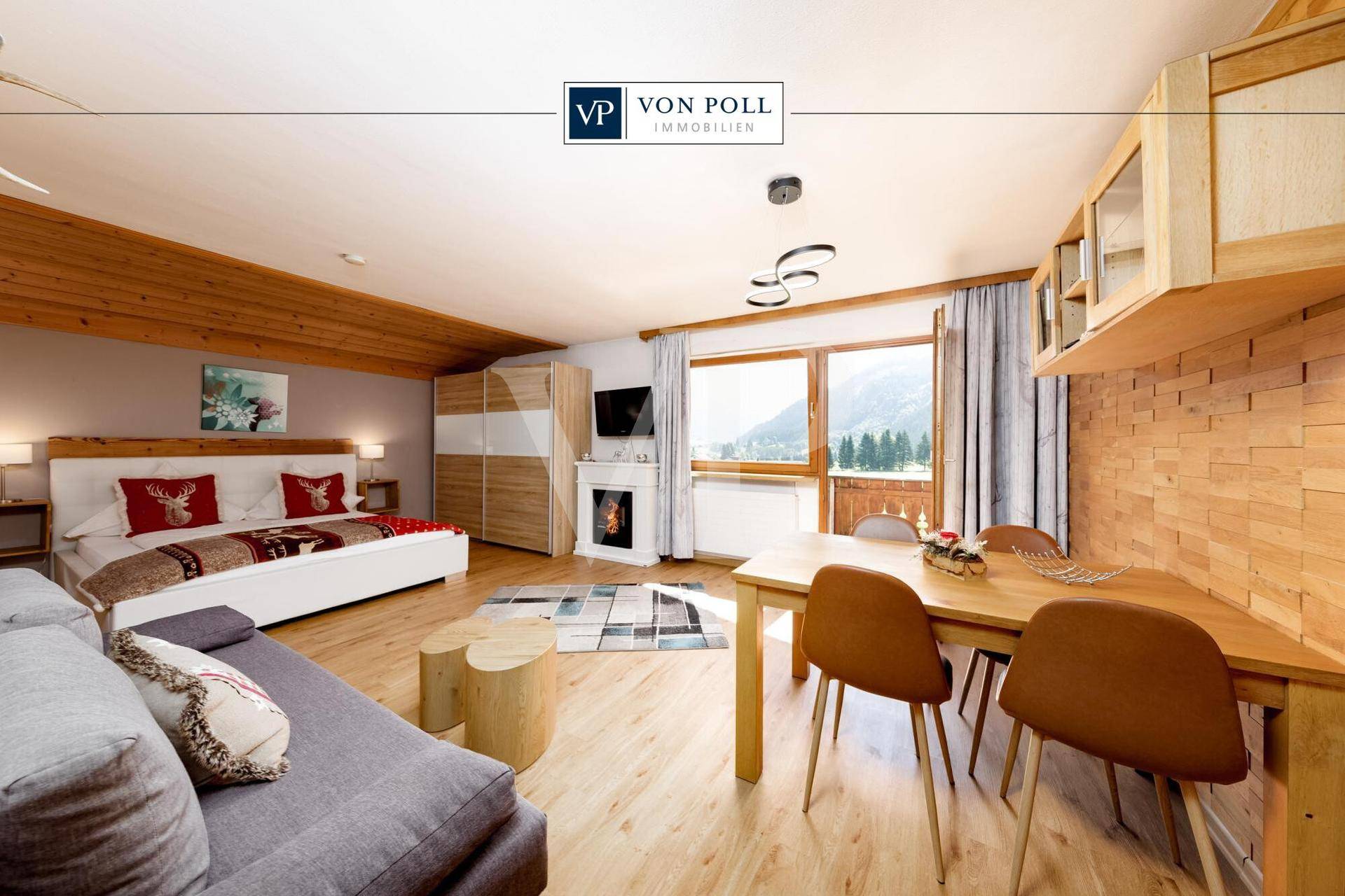 Helles Schlafzimmer mit Doppelbett, kleinem Essbereich und Zugang zu einem Balkon mit Bergblick.
