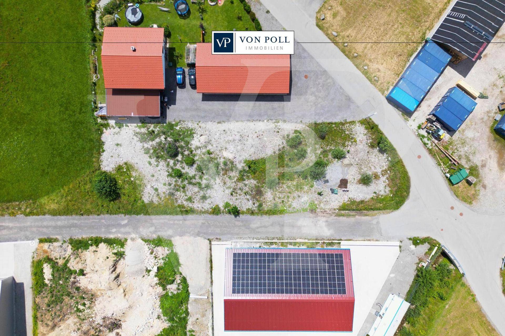 Draufsicht auf mehrere Gebäude mit roten Dächern und Solaranlagen in ländlicher Umgebung.