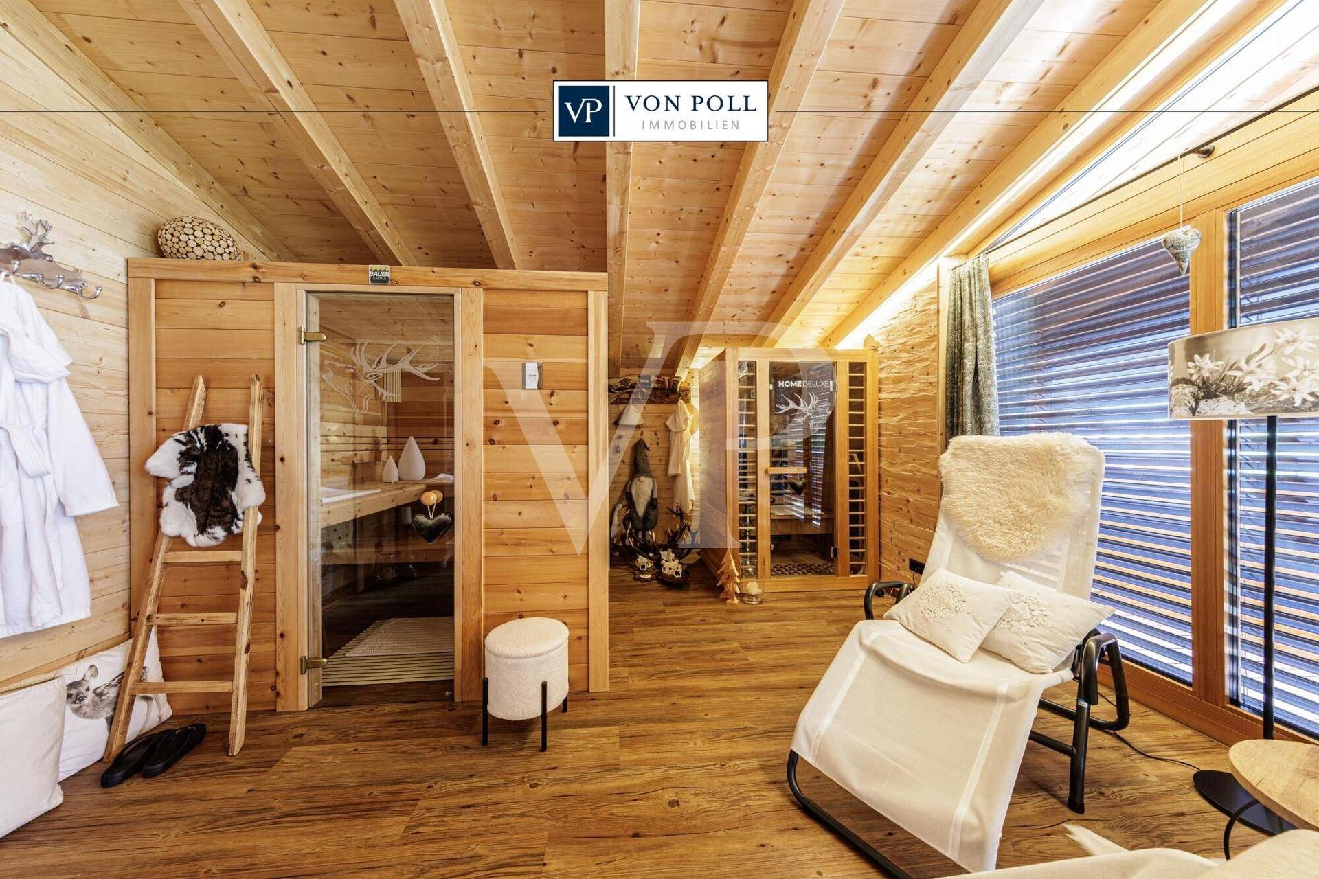 Entspannungsbereich mit Holzsauna, Liegestuhl und großen Fenstern, umgeben von alpiner Holzverkleidung.
