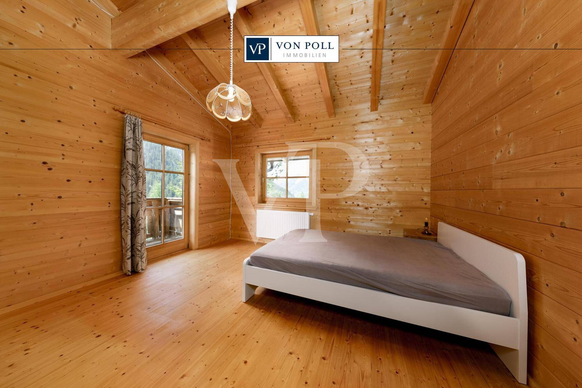 Helles Schlafzimmer im alpinen Stil mit Holzboden, Holzwänden und Zugang zu einem Balkon.