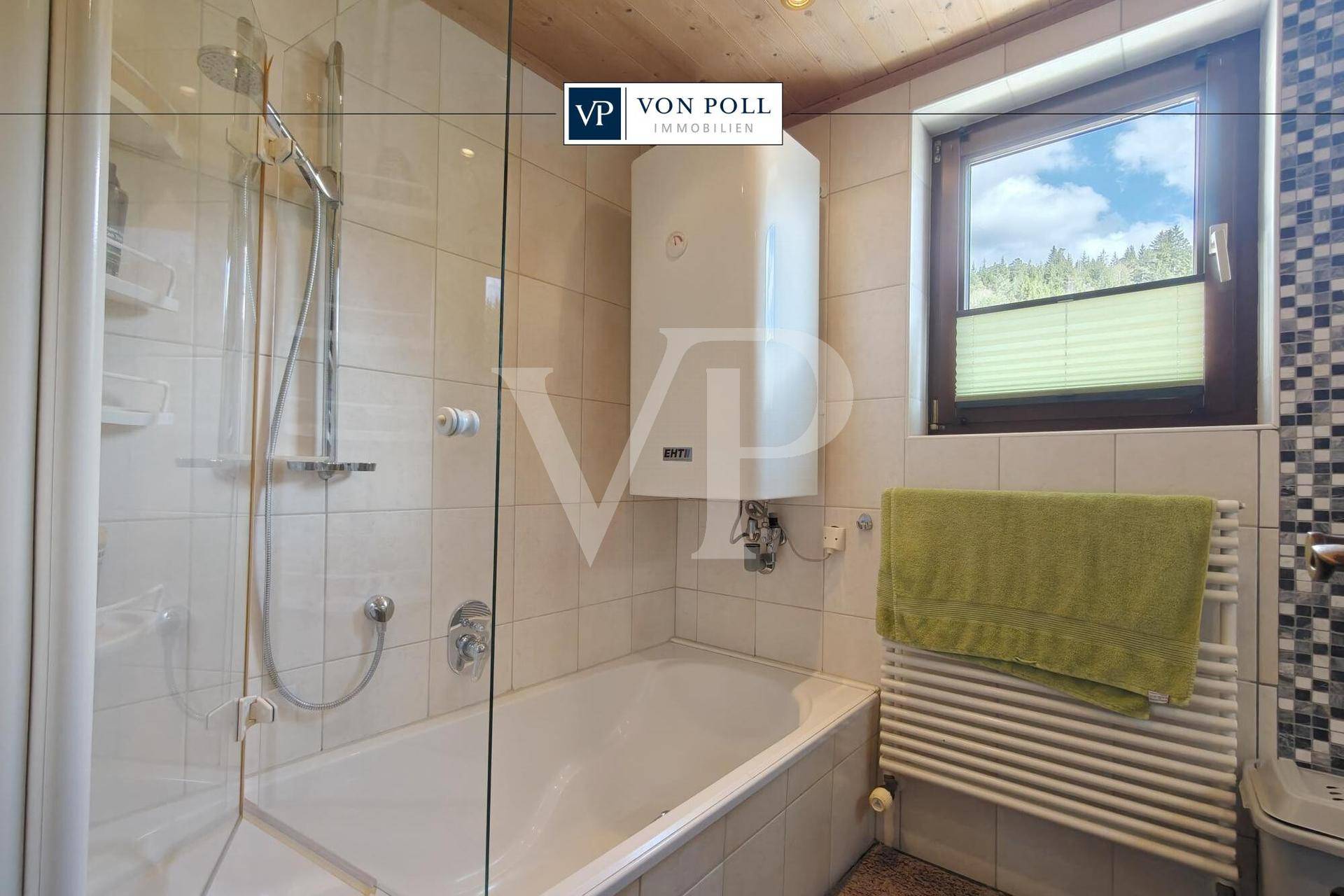 Badezimmer mit Badewanne, Duschkabine, Fenster und beheiztem Handtuchhalter.