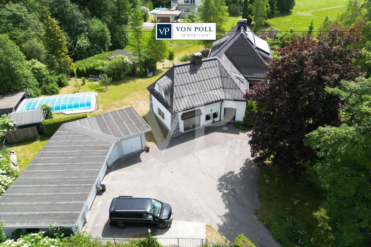 Luftaufnahme eines Anwesens mit Haus, Doppelgarage, Pool und weitläufiger Grünfläche.