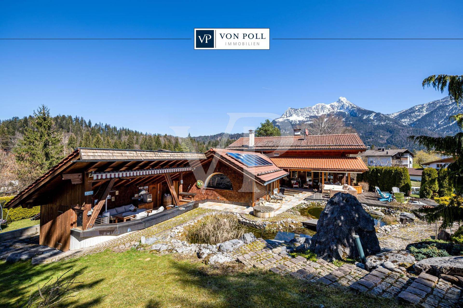 Großzügiges Anwesen mit Haupthaus, überdachtem Außenbereich, Teich und beeindruckendem Bergblick.