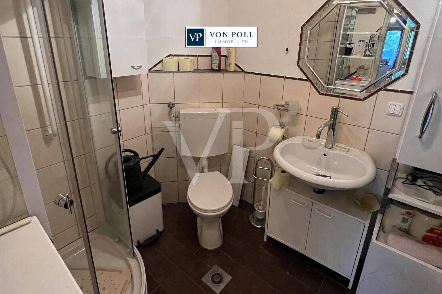 Badezimmer mit Dusche, WC, Waschbecken und Fliesen an Wänden und Boden im 80er-Jahre-Stil.