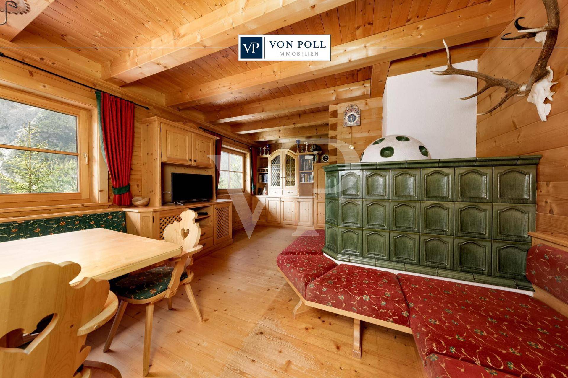 Traditionelles Wohnzimmer im alpinen Stil mit Kachelofen, Holzboden und rustikalen Möbeln.
