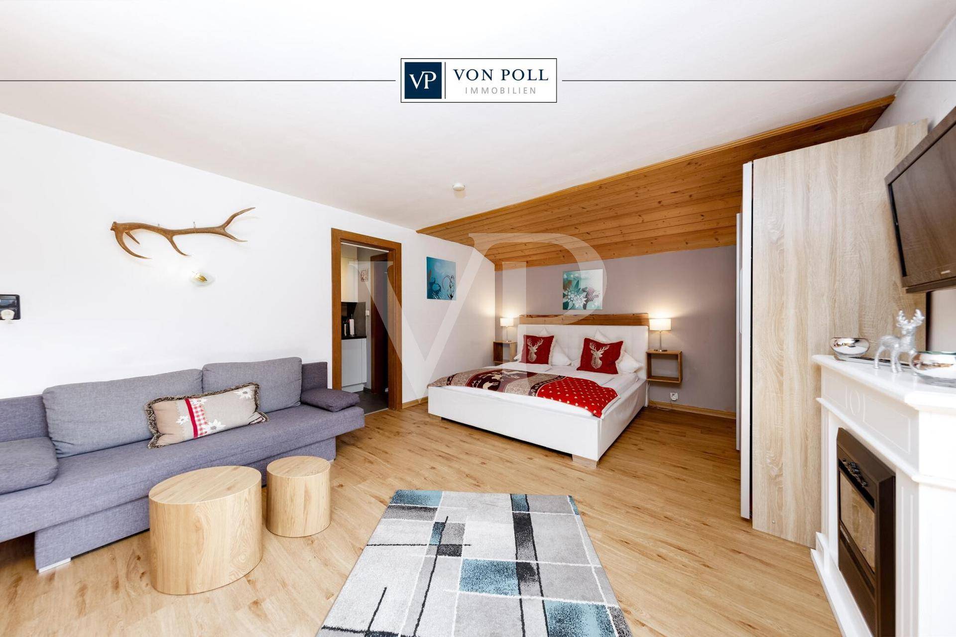 Helles Schlafzimmer mit Doppelbett, Sofa und dekorativem Kamin, im alpinen Stil eingerichtet.