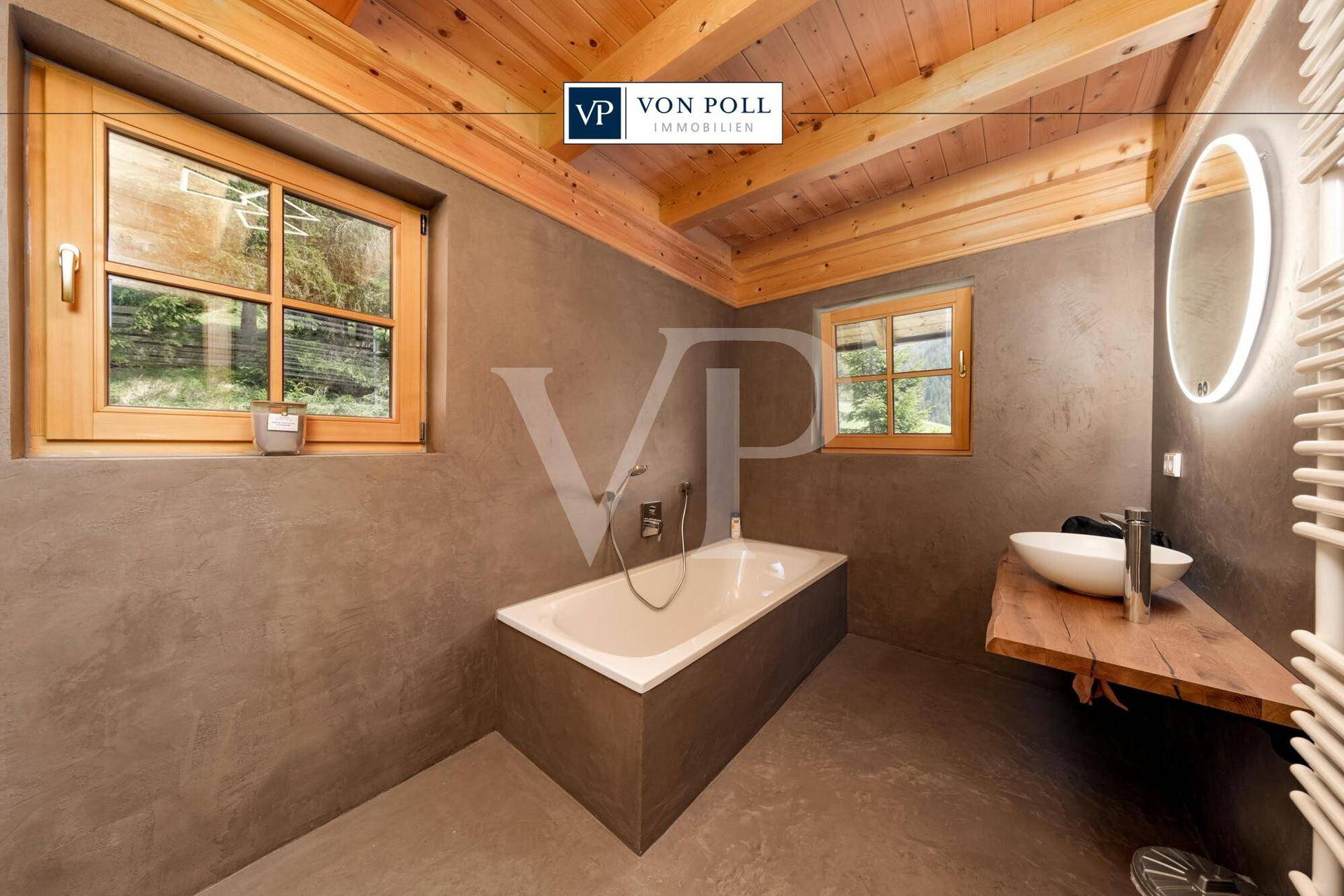 Modernes Badezimmer mit Badewanne, Holzbalkendecke und einem stilvollen Waschbecken auf einer Holzplatte.