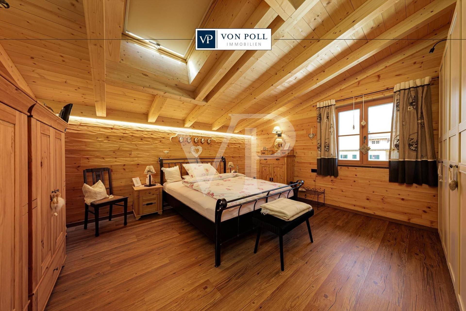 Gemütliches Schlafzimmer mit Holzwänden, Holzbalkendecke, Dachfenster und Doppelbett im alpinen Stil.
