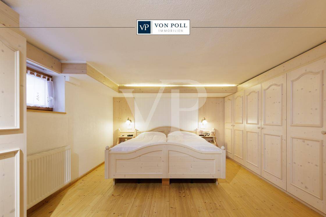 Gemütliches Schlafzimmer mit hellem Holzboden, Einbauschränken und indirekter Beleuchtung.