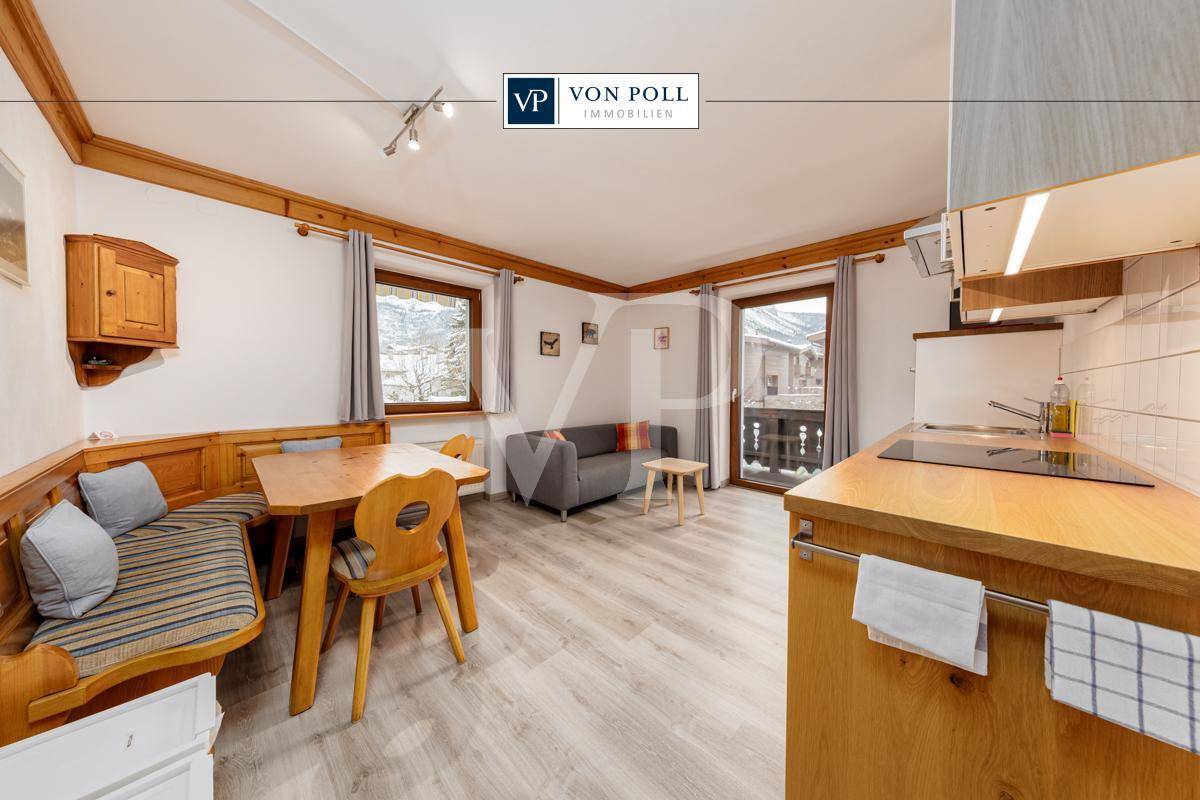 Gemütlicher Wohn-Essbereich im Landhausstil mit Holzelementen, Sitzecke und kleiner Küchenzeile.