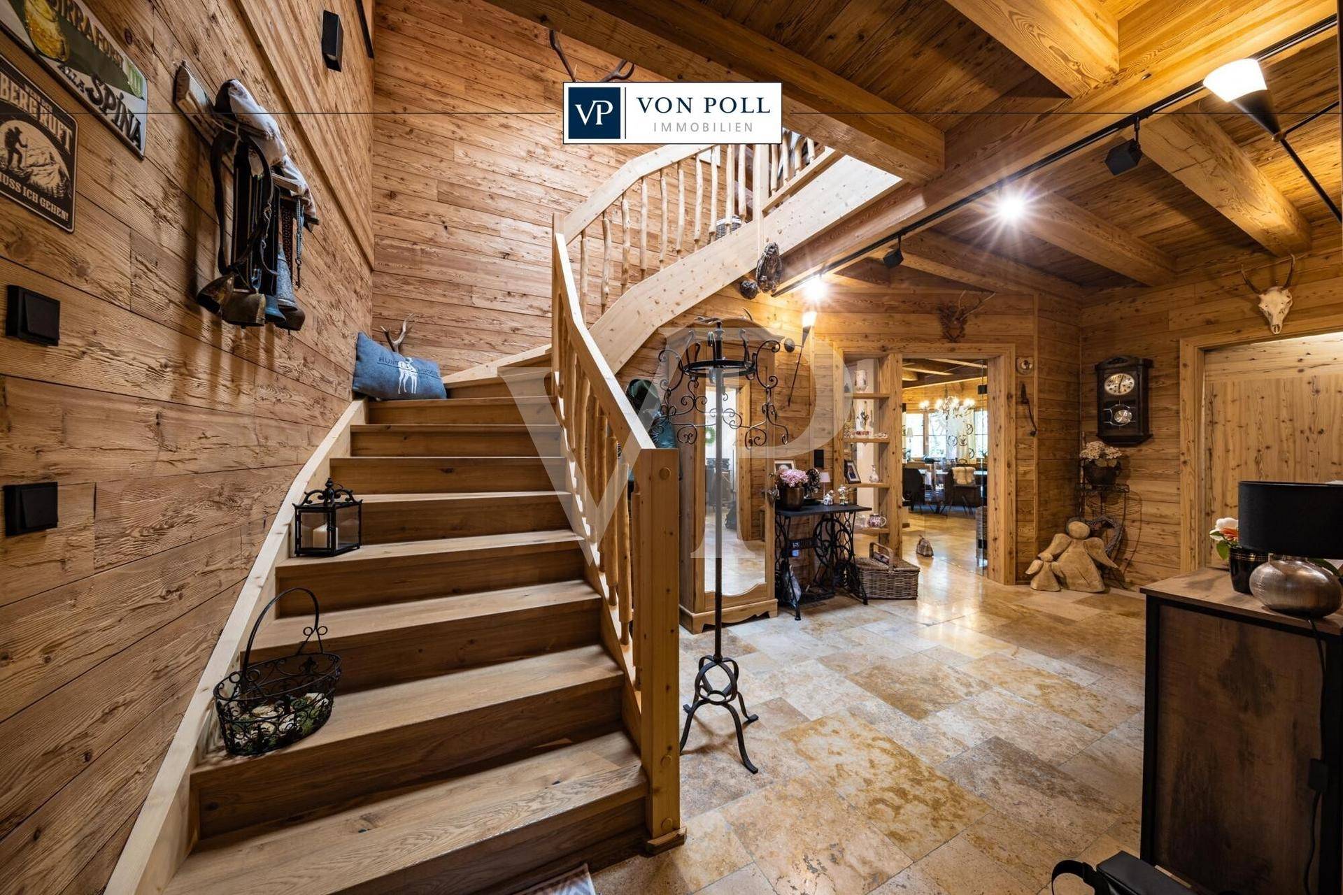 Rustikaler Eingangsbereich mit geschwungener Holztreppe, Holzwänden und Steinboden im alpinen Stil.