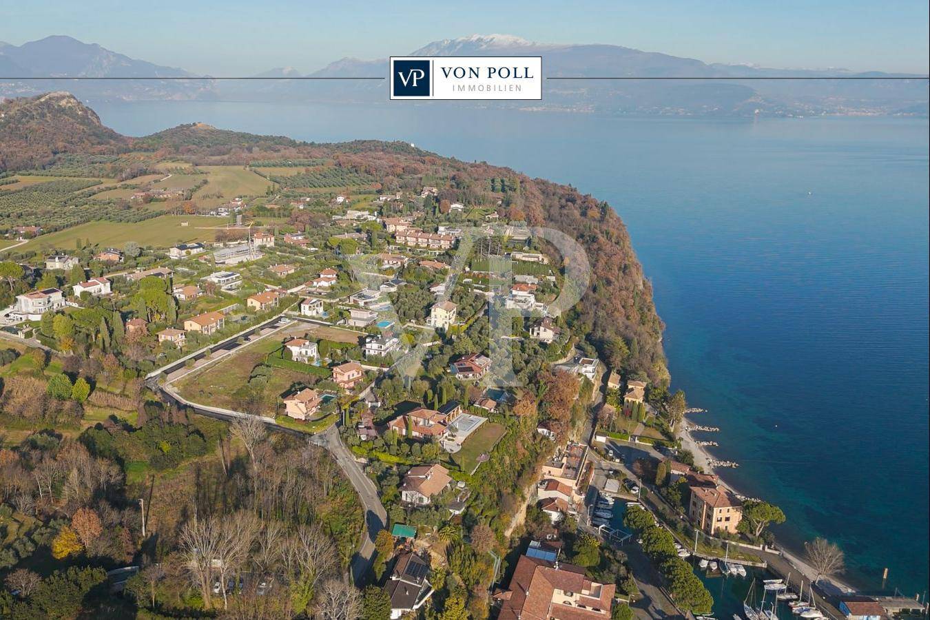 Panoramablick auf die Küste mit See, Bergen und umliegenden Wohnhäusern in sonniger Umgebung.