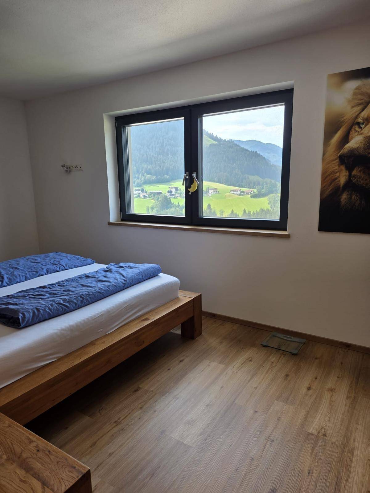 Gemütliches Schlafzimmer mit Holzbett, Holzboden und einem weiten Blick auf die umliegende Berglandschaft.