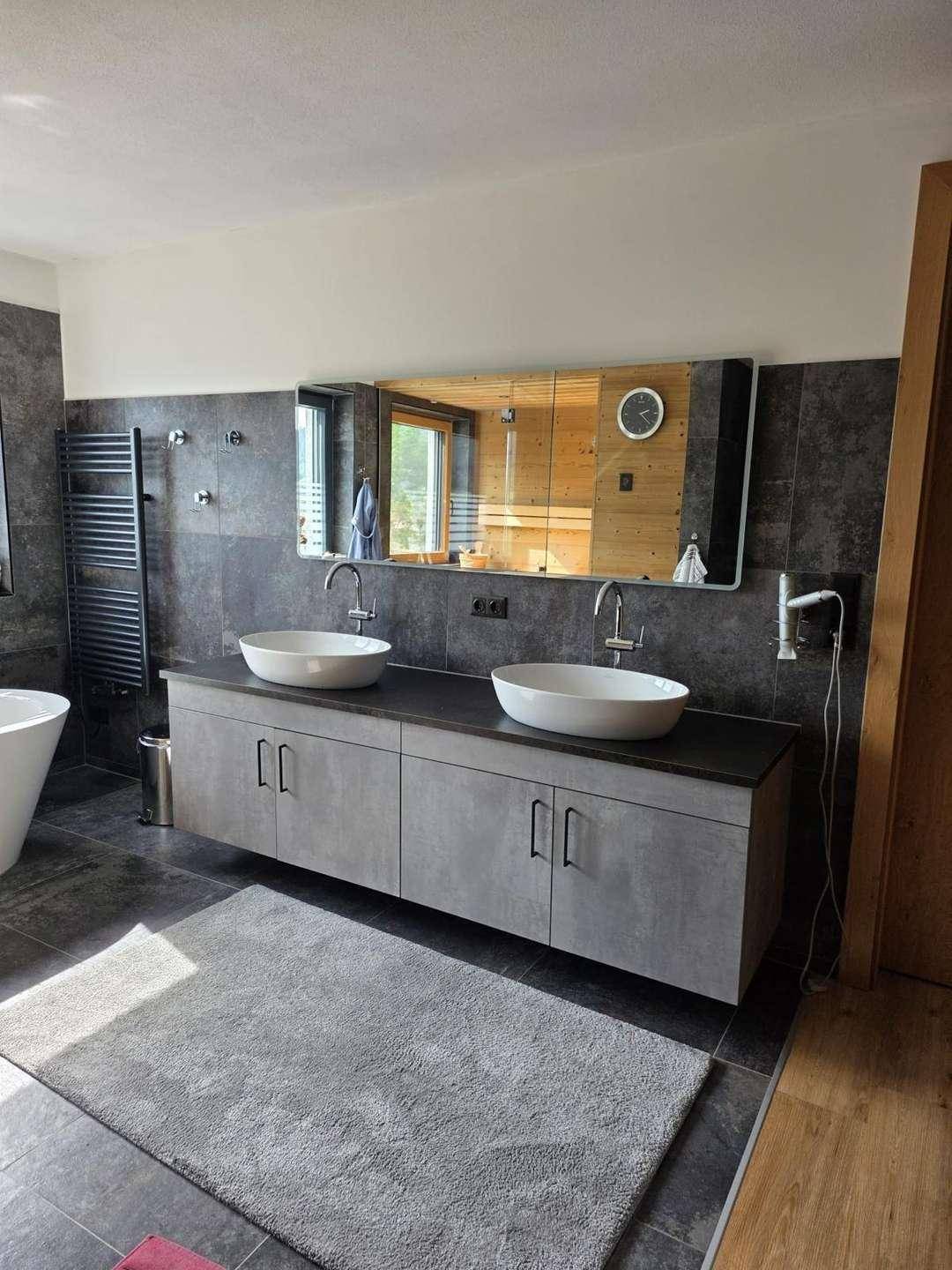 Modernes Badezimmer mit Doppelwaschtisch, großem Spiegel und beheiztem Handtuchhalter.