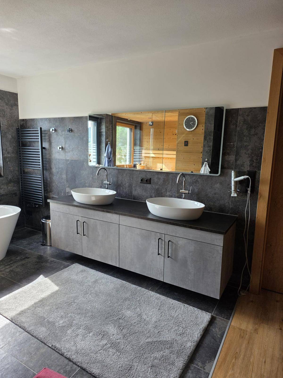Elegantes Badezimmer mit Doppelwaschbecken, großem Spiegel und beheiztem Handtuchhalter.