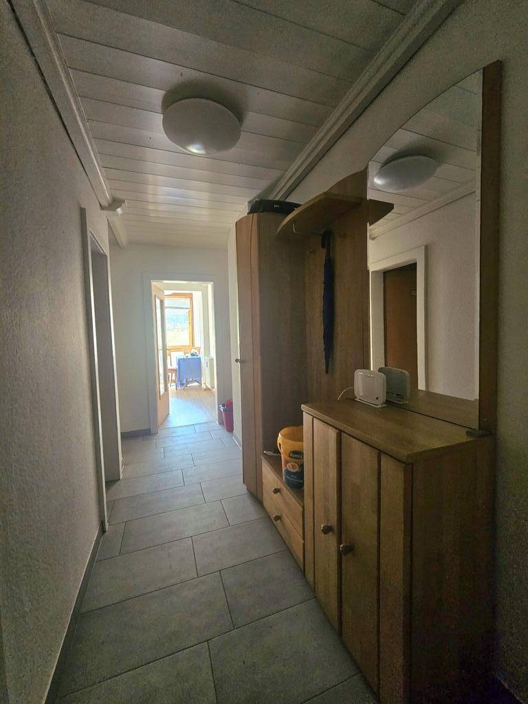 Heller Flur mit Fliesenboden, Holzdecke und Garderobe, der zu weiteren Räumen führt.