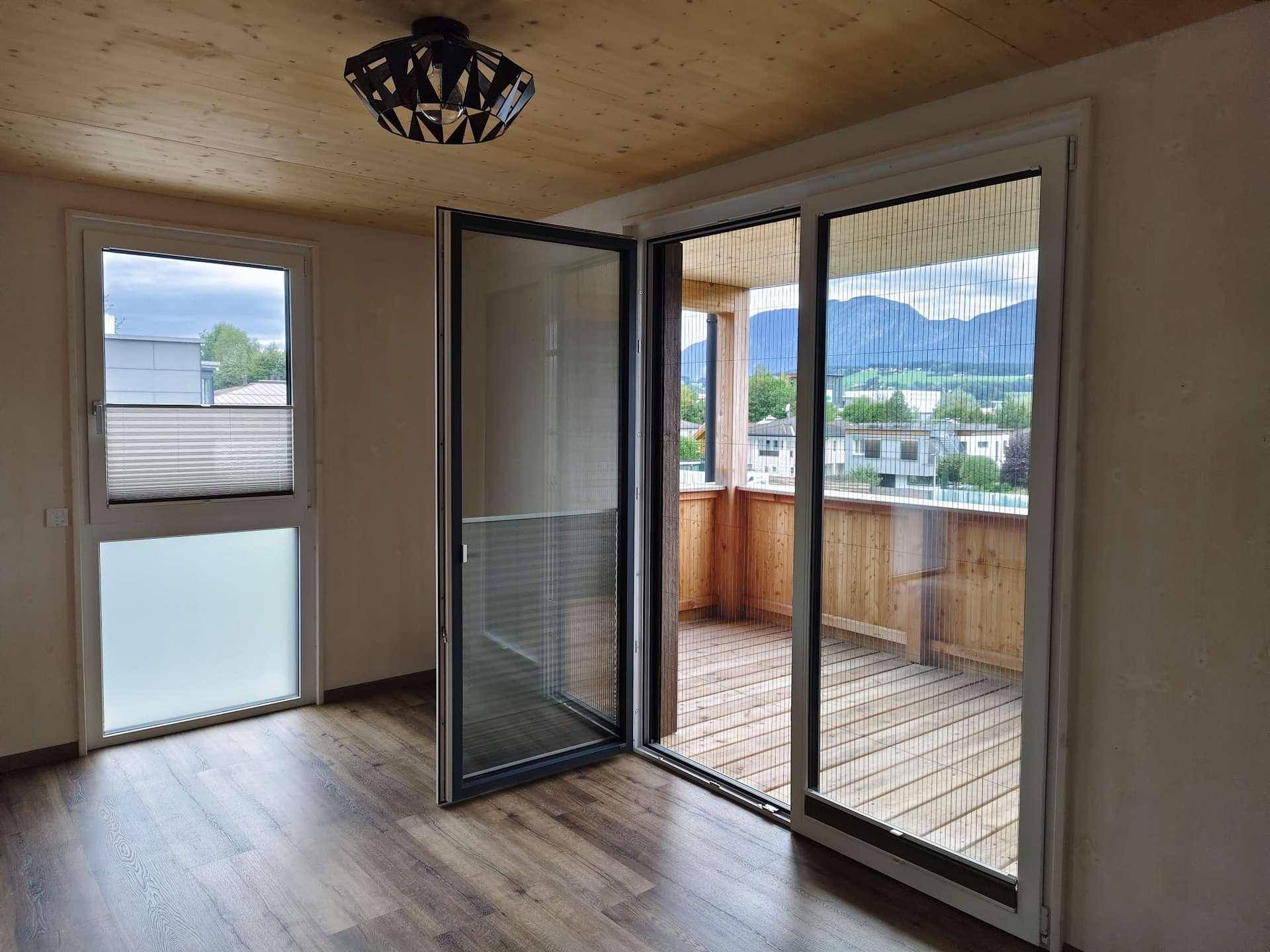 Geräumiges Zimmer mit Holzbalkendecke, Laminatboden und Zugang zu einem Balkon mit Bergblick.