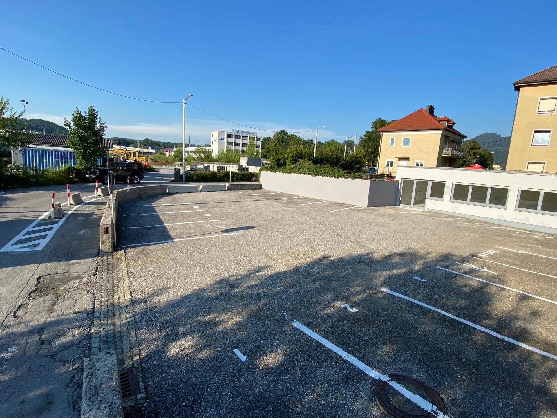 Großer Außenparkplatz mit markierten Stellplätzen und umliegender Bebauung.