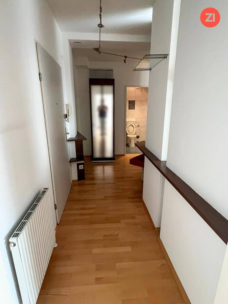 Heller Flur mit Holzfußboden, weiß gestrichenen Wänden und Zugang zu weiteren Räumen.