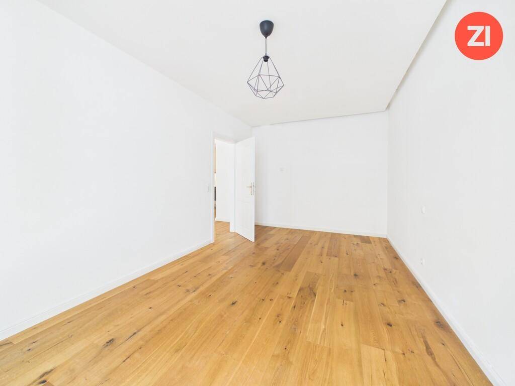 Leeres Zimmer mit Holzboden und Zugang zu weiteren Räumen, vielseitig nutzbar.