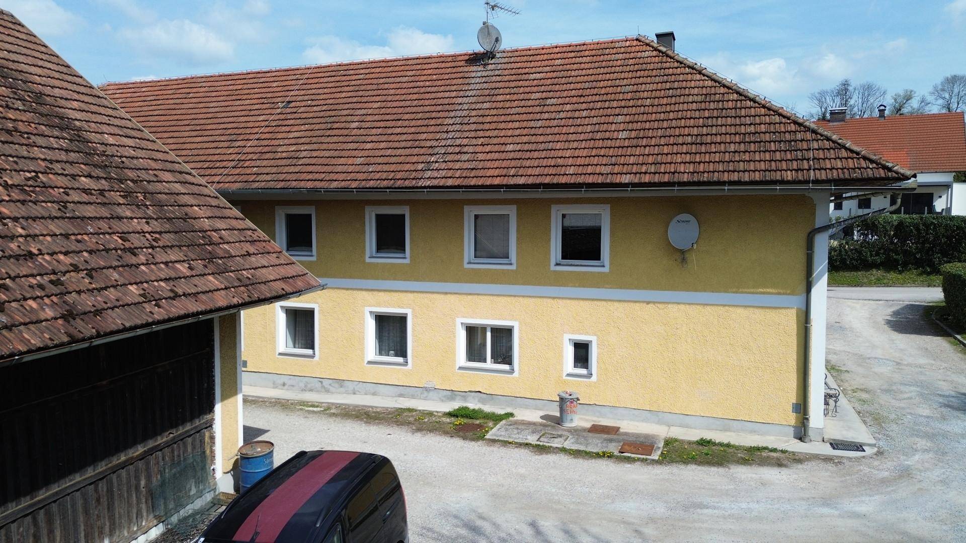 Seitenansicht des gelben Gebäudes mit Ziegeldach und Satellitenschüssel, daneben ein weiteres Gebäude.