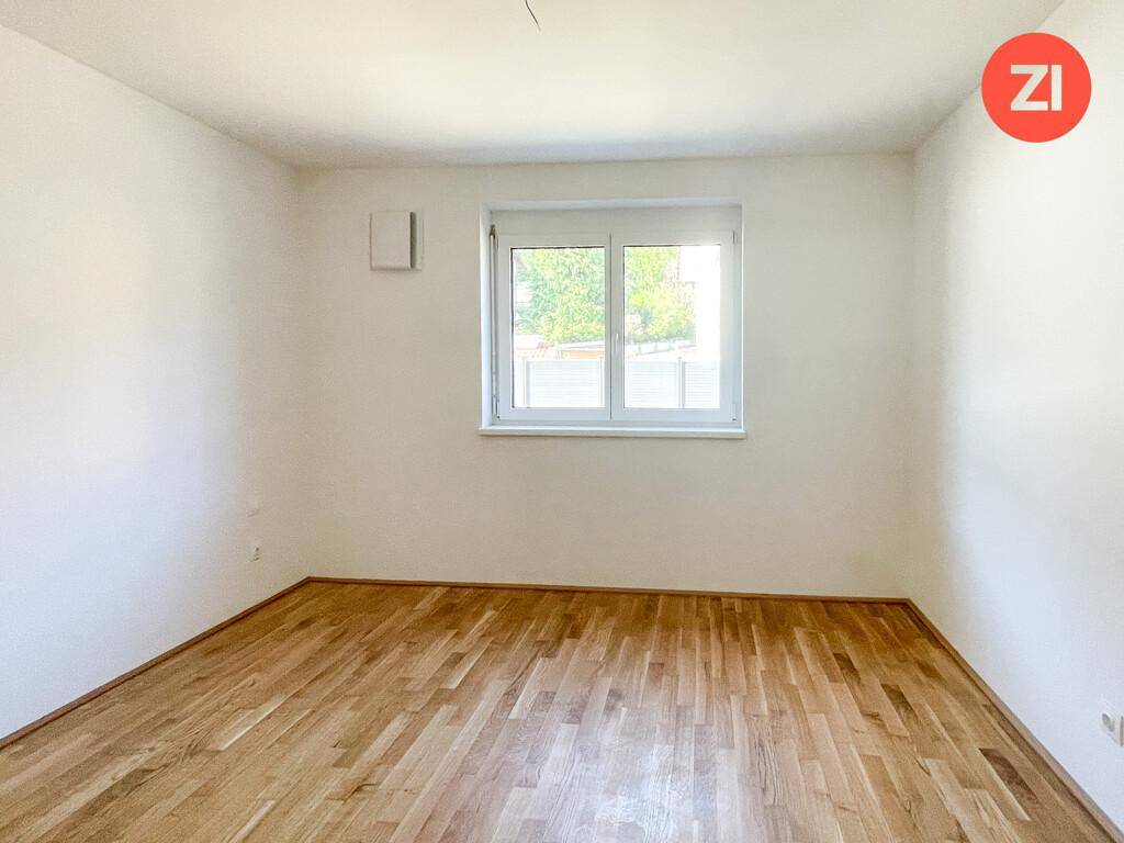 Unmöbliertes Zimmer mit hellem Parkettboden und einem Fenster, bereit zur individuellen Gestaltung.