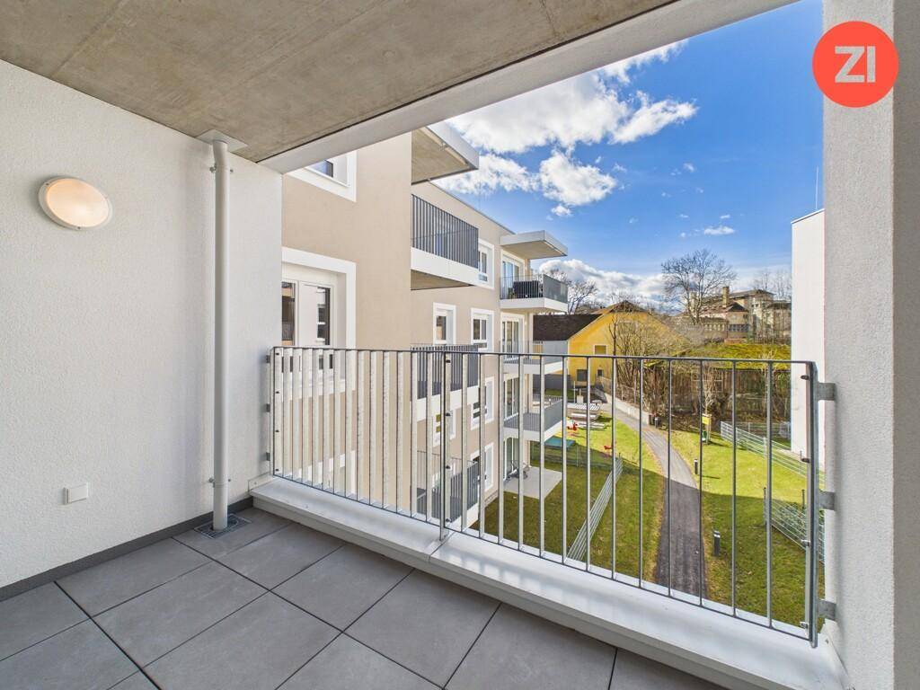 Geräumiger Balkon mit Fliesenboden und Blick auf die grüne Umgebung und andere Gebäude.