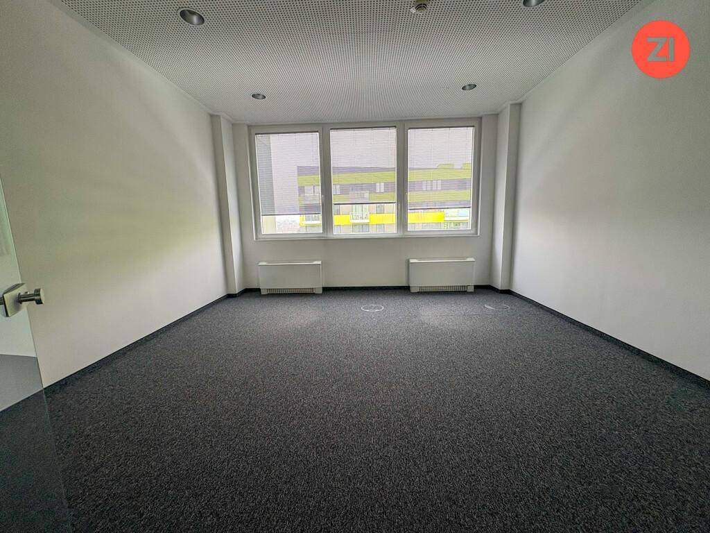Helles Einzelbüro mit Teppichboden, großen Fenstern und Blick auf die Umgebung.