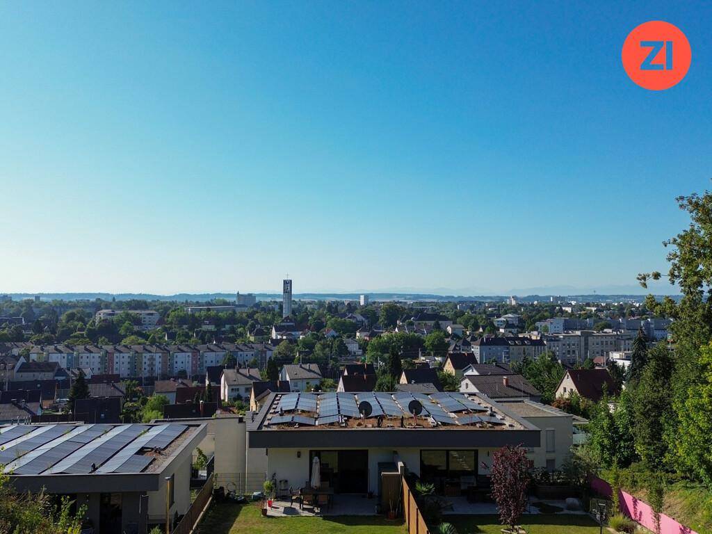 Luftaufnahme einer modernen Wohnsiedlung mit Häusern, Solaranlagen und Stadtpanorama.