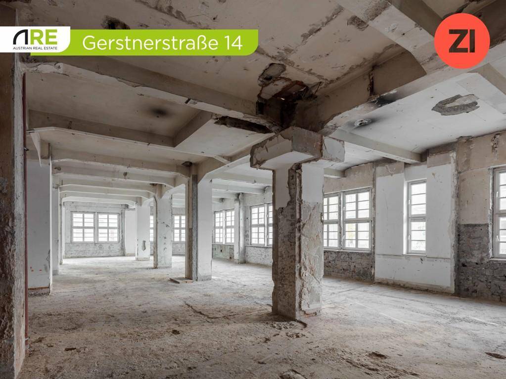 Großer, leerer Gewerberaum mit Betonpfeilern und vielen Fenstern, in sanierungsbedürftigem Zustand.