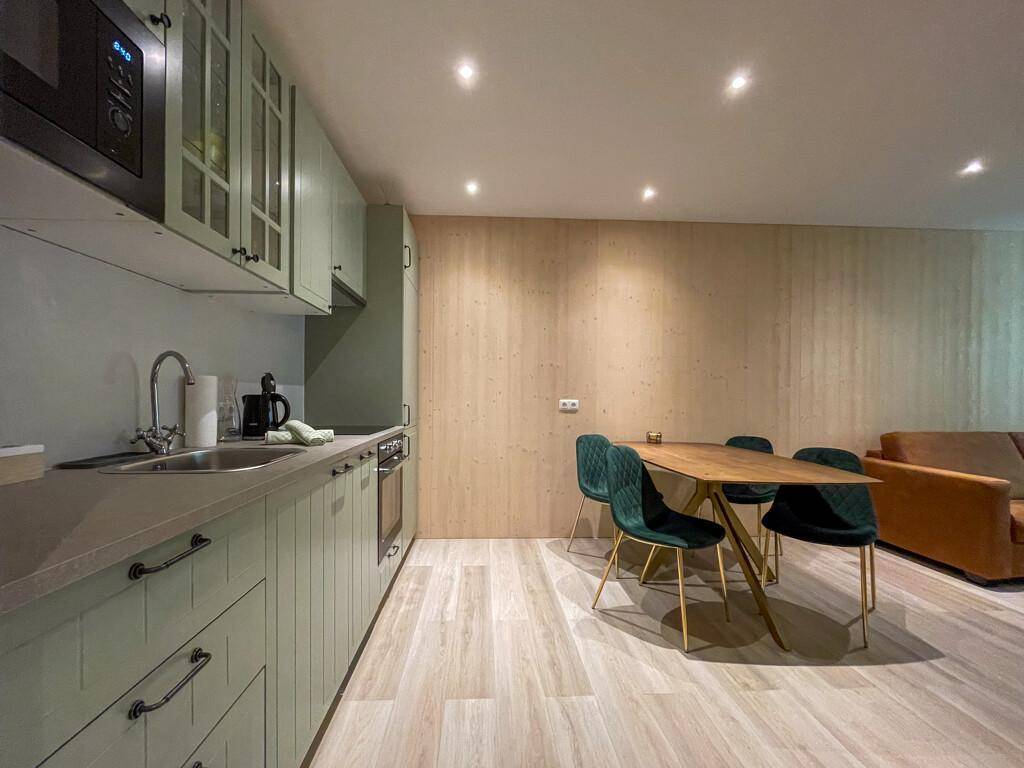 Helle Küche mit Essbereich und Holzwand, ausgestattet mit modernen Geräten.