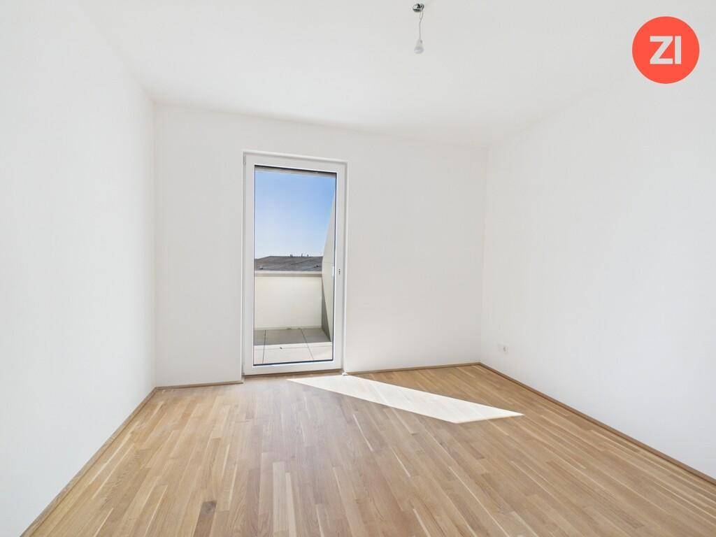 Ein weiteres helles Zimmer mit Holzboden und Zugang zu einem Außenbereich, ideal als Schlaf- oder Arbeitszimmer.