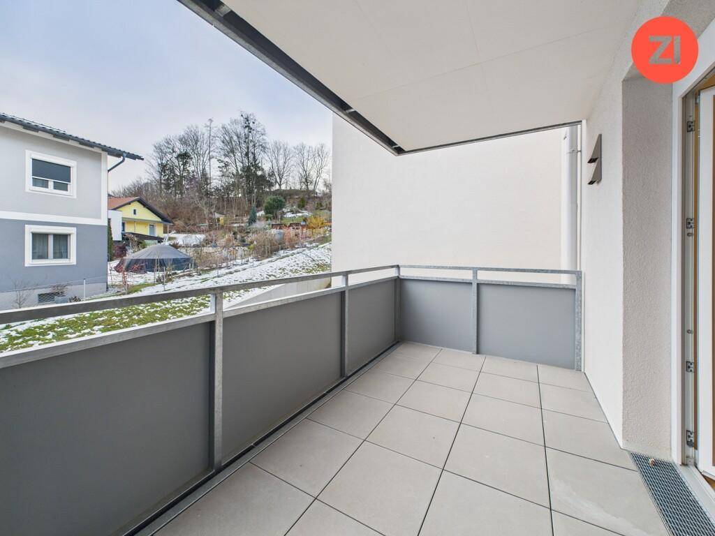 Geräumiger Balkon mit Fliesenboden und Blick auf die verschneite Umgebung und Häuser.