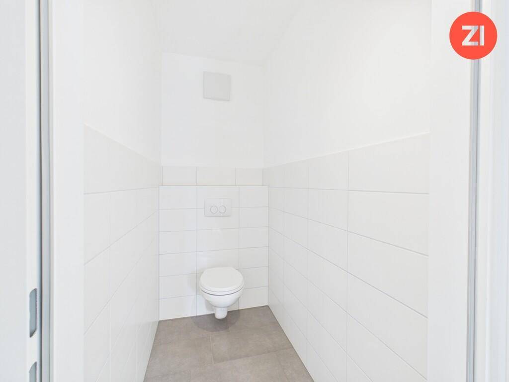 Separates Gäste-WC mit wandhängender Toilette und weißen Fliesen an den Wänden.