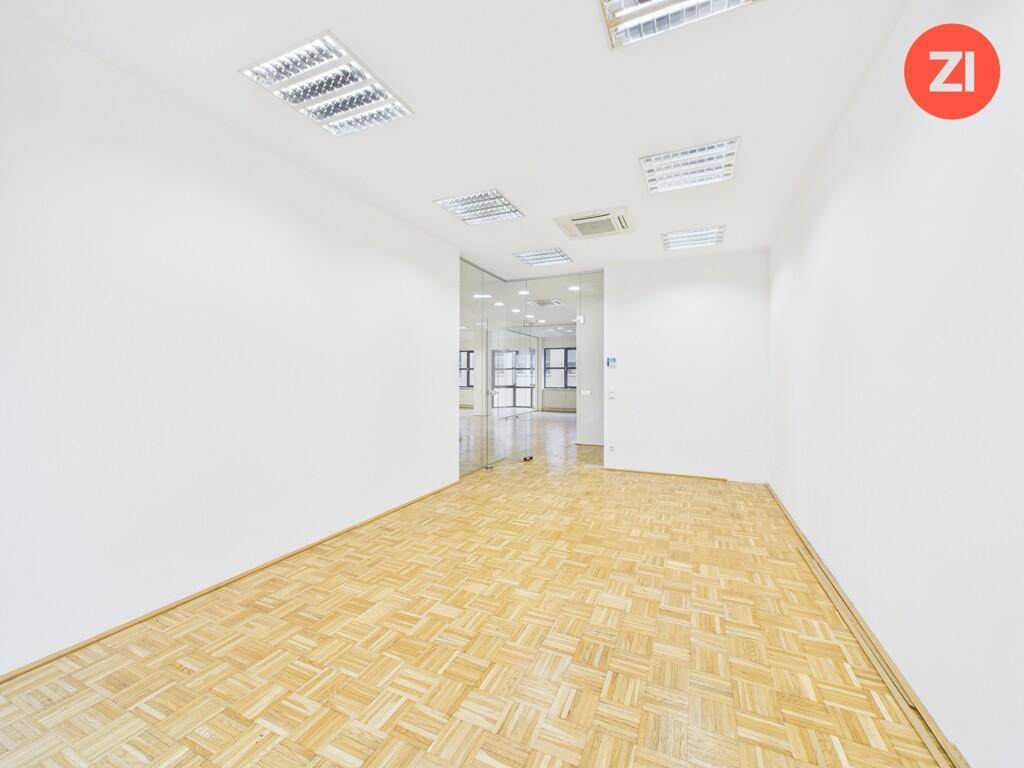 Offener Bürobereich mit hellem Parkettboden und modernen Glaswänden, die eine flexible Raumgestaltung ermöglichen.