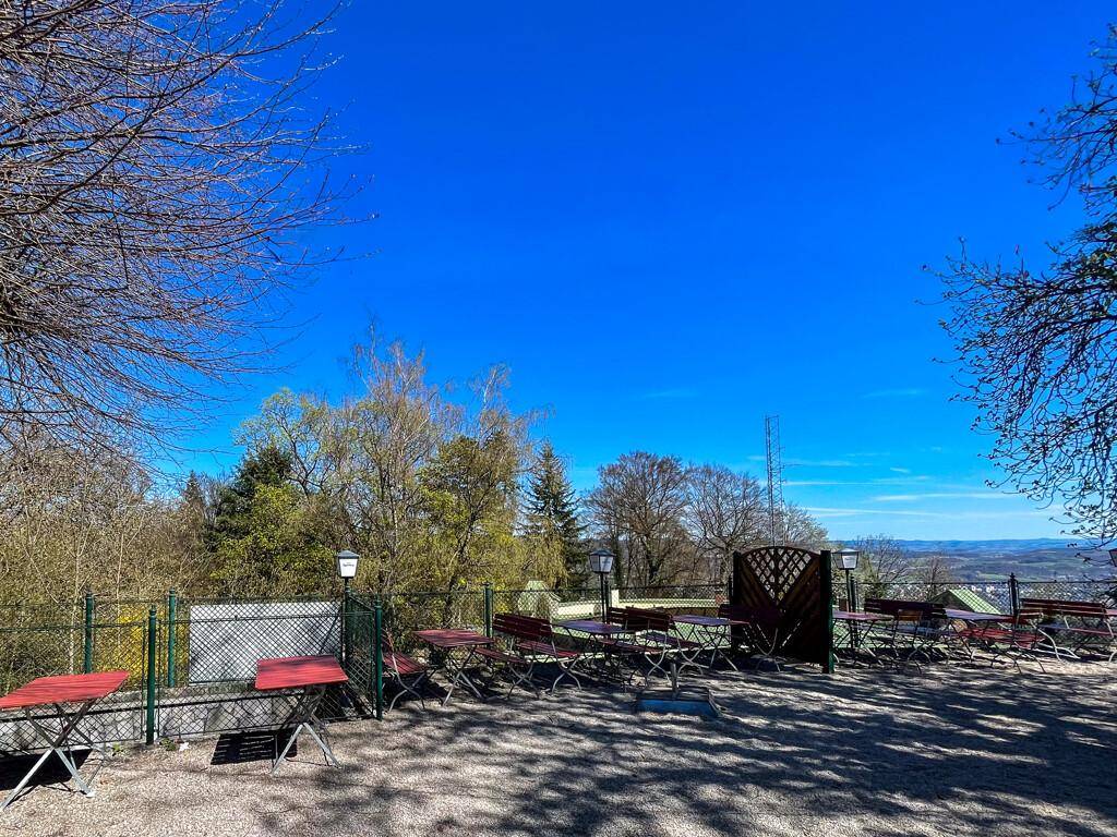 Gemütliche Außenterrasse mit Tischen und Stühlen, die einen weiten Blick in die Landschaft bietet.