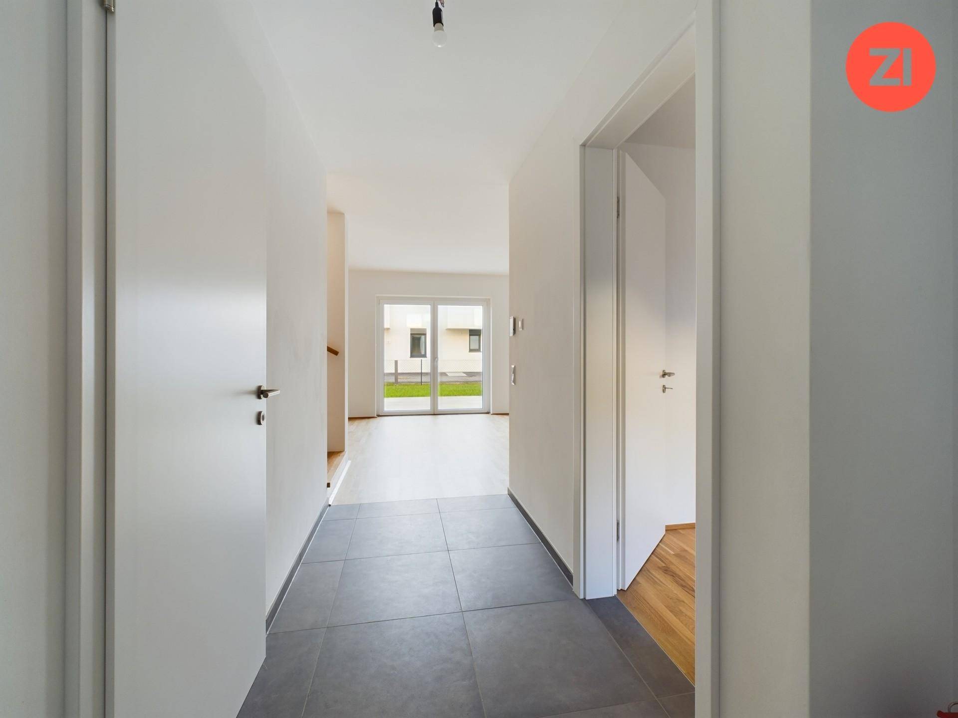 Eingangsbereich mit Fliesenboden, der zu einem hellen Wohnbereich mit Gartenzugang führt.