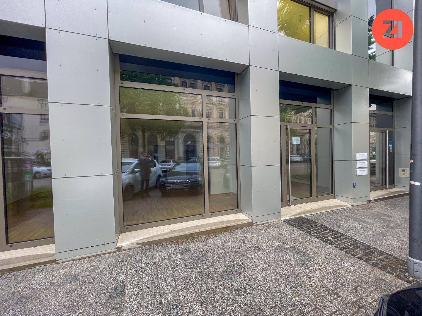 Fassade eines modernen Geschäftsgebäudes mit großen Schaufenstern und grau-metallischen Verkleidungen.