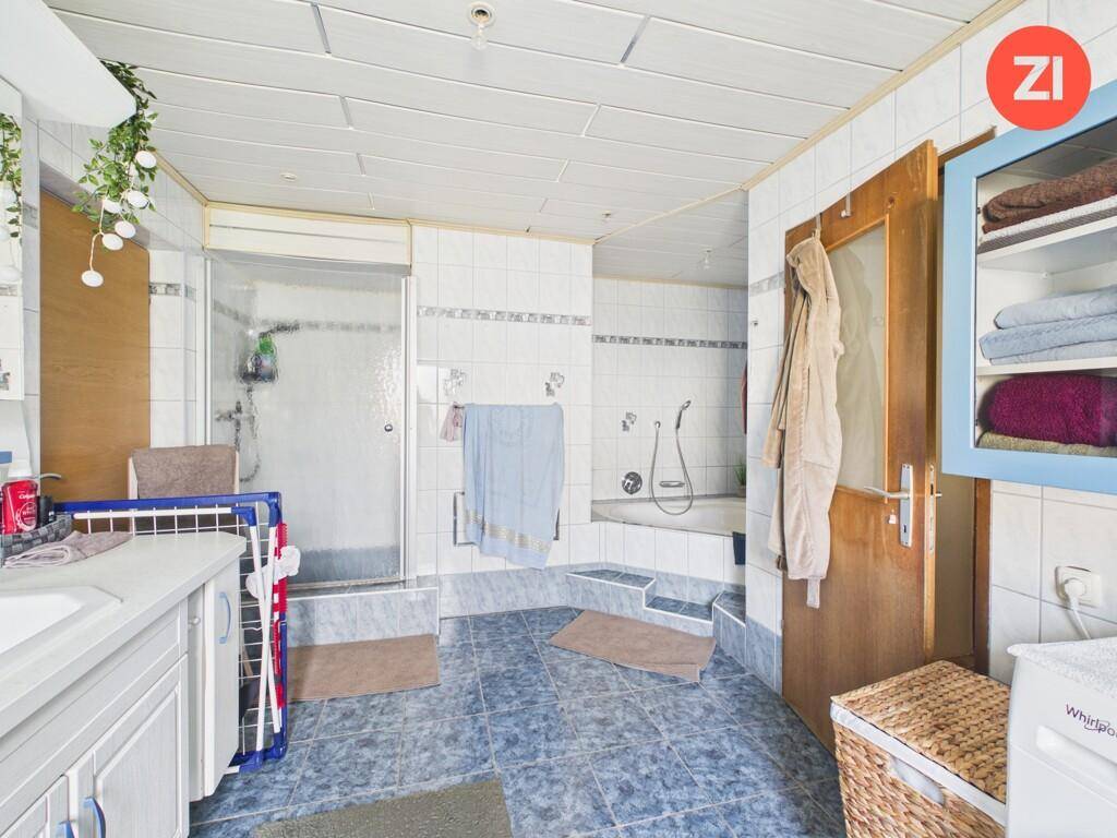 Badezimmer mit Badewanne, Duschkabine und blauen Bodenfliesen.