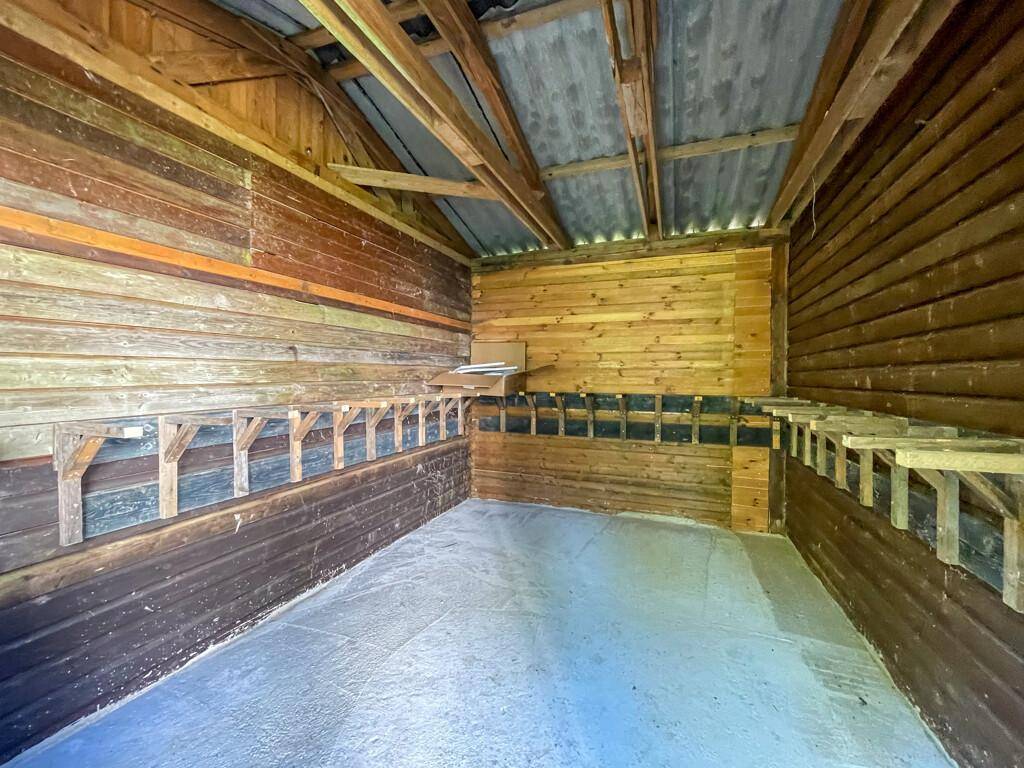 Rustikaler Holzschuppen mit Regalen und Holzbalken, ideal als Abstellraum oder Werkstatt.
